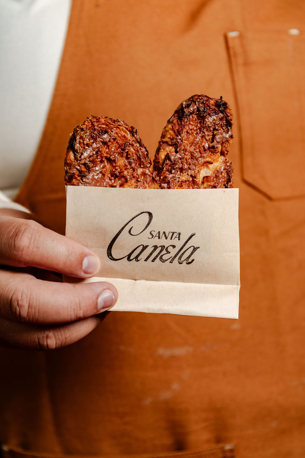 Chocolate-dipped churros in a Santa Canela paper bag