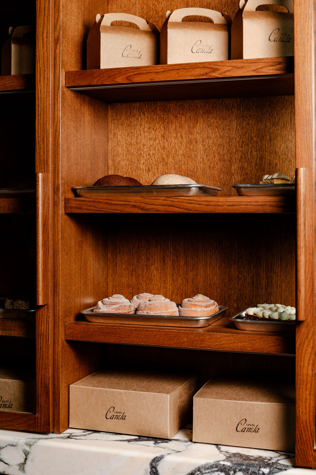 Pastry boxes and trays of cinnamon rolls on the shelves