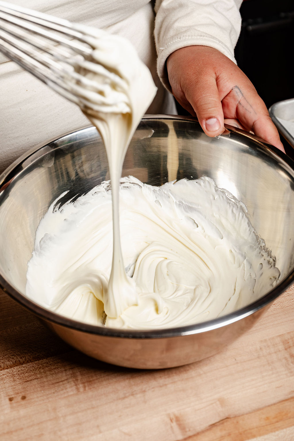 Vanilla frosting ribboning off a whisk