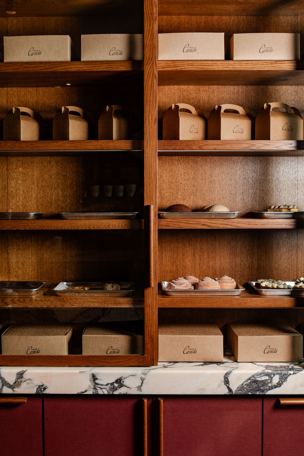 The oak shelving wall stacked with pastry boxes and trays